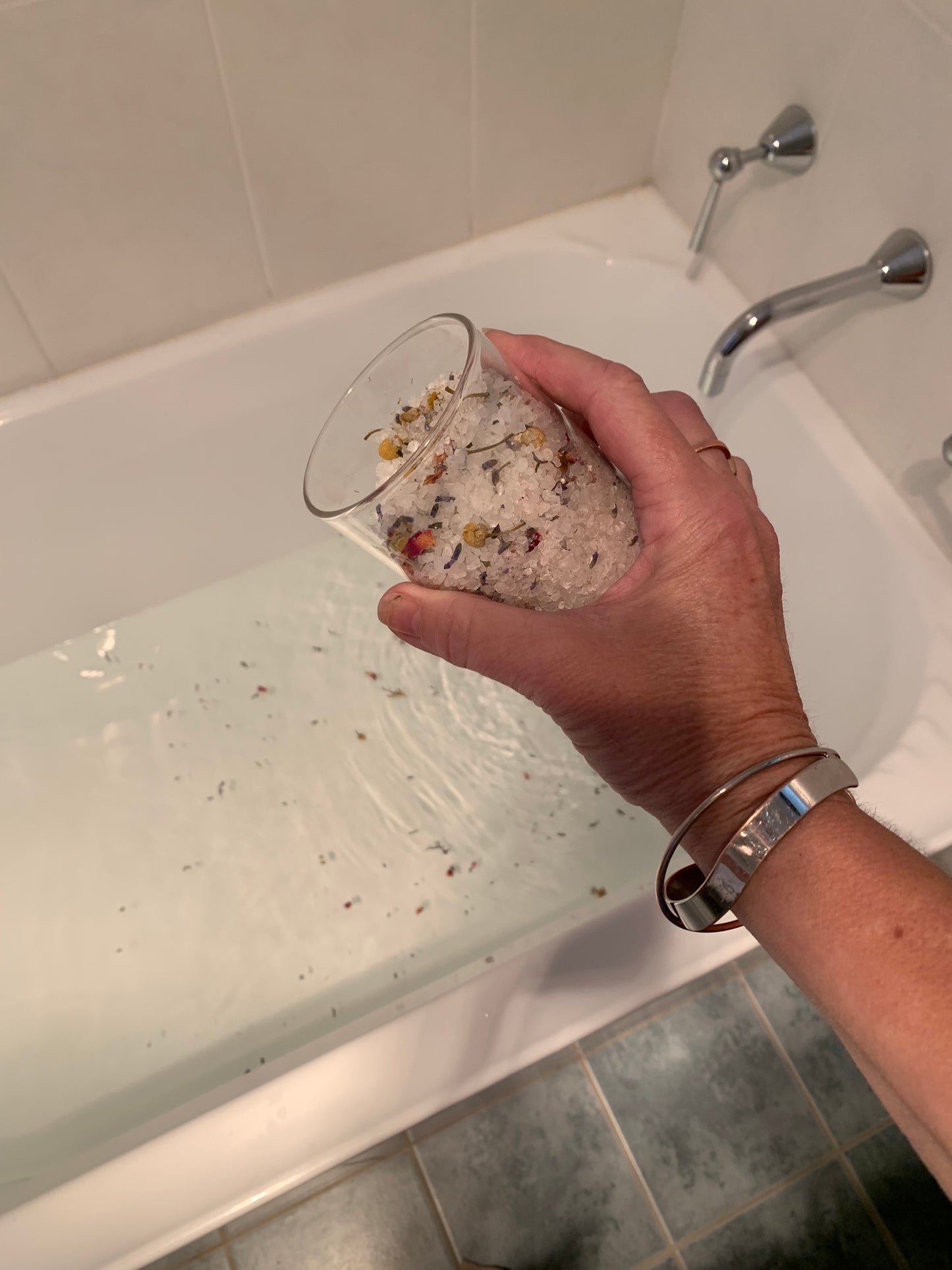 A Glass jar of "relax" bath salts being sprinkled into the bath.